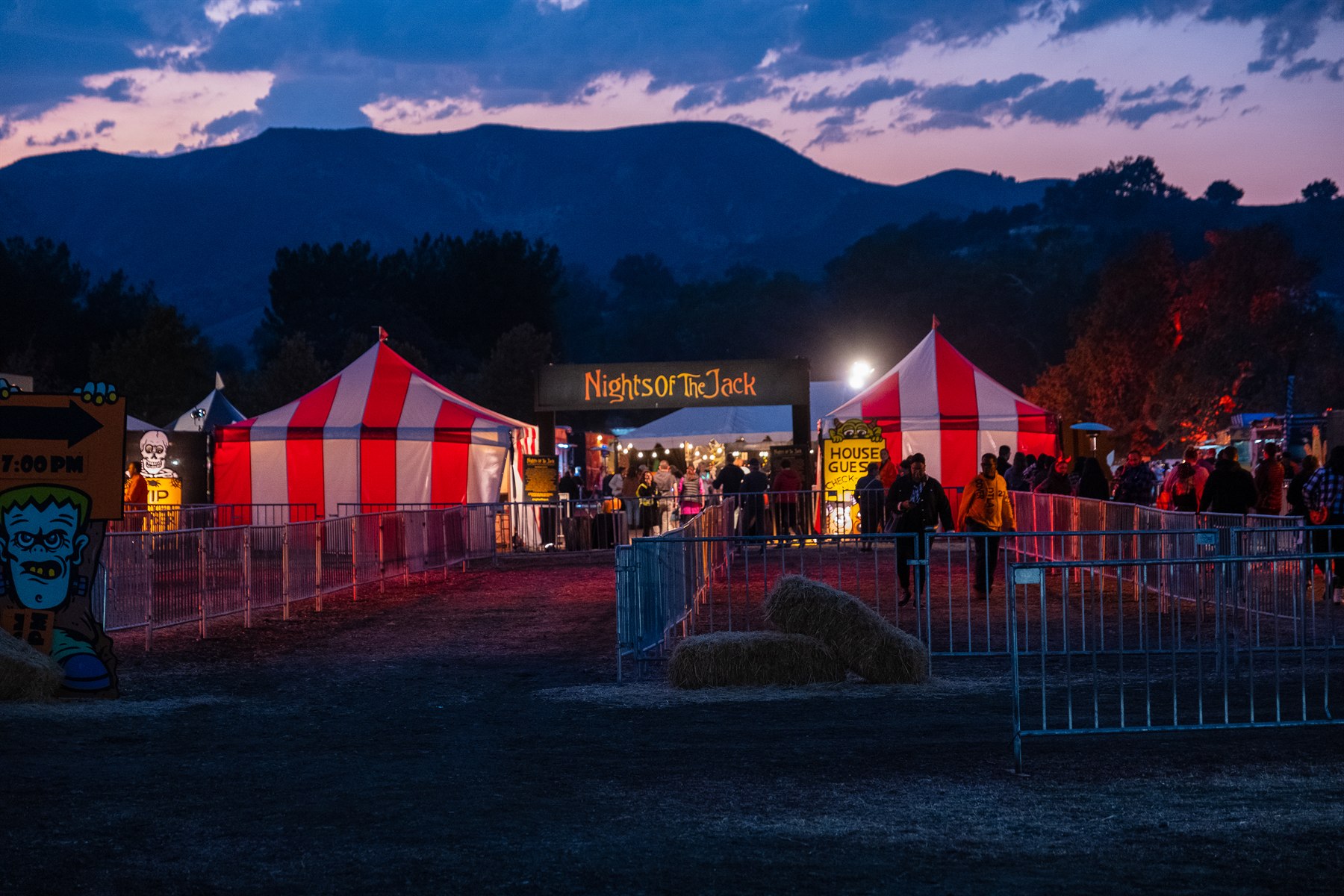 Guests arriving at a nighttime outdoor event beneath mountains.